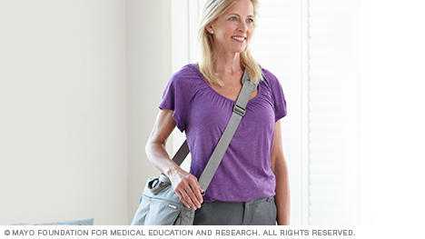 A woman carrying a large purse by its shoulder strap across her body