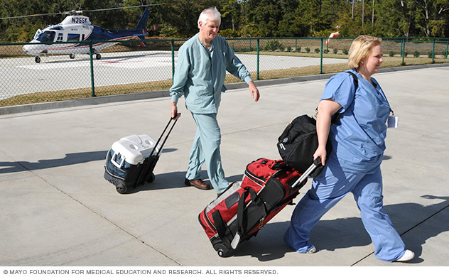 Two Mayo staff members walking with coolers from a helicopter.