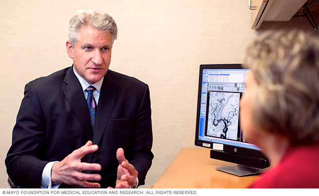 A doctor converses with a woman about brain aneurysm.