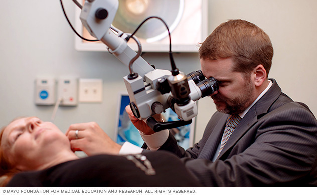 An ear doctor (otologist) conducts an ear exam