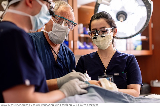 A team performs a dermatologic procedure.