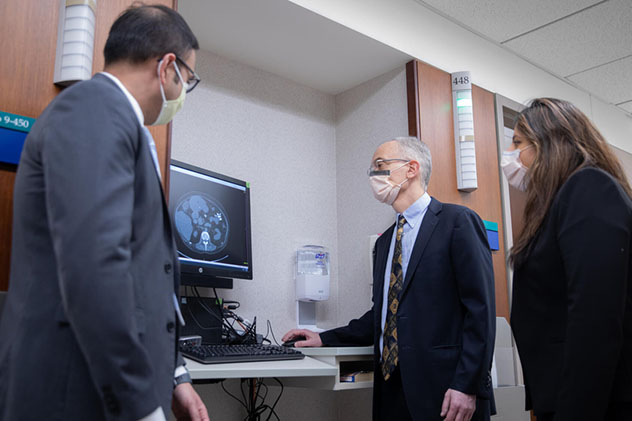 Pancreas Clinic specialists review scan images on a hall monitor.