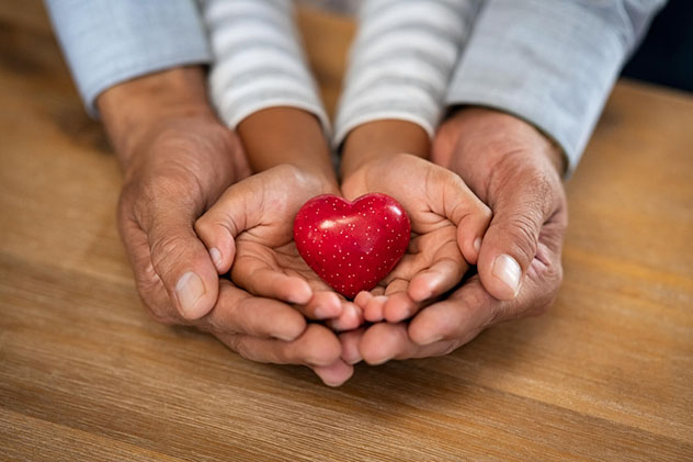 A child's hands nest within an adult's hands.