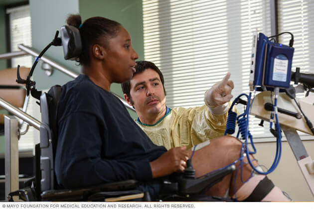 A therapist works with a seated patient.