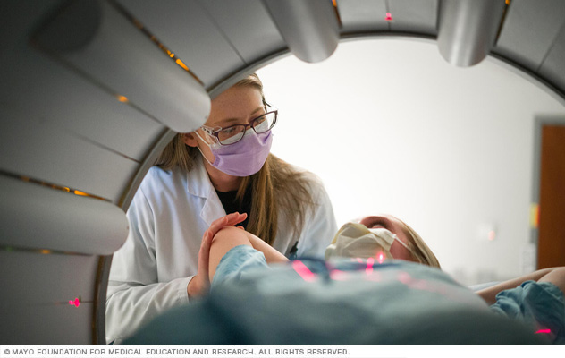 A member of the health care team talks with a patient before a SPECT scan.