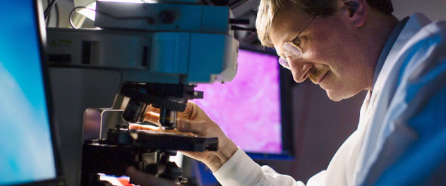 Photograph of Dr. Fergus Couch using a microscope to examine samples