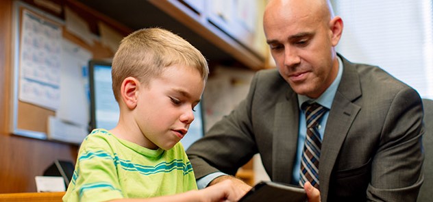 Dr. Whiteside works with a young boy using a tablet device.