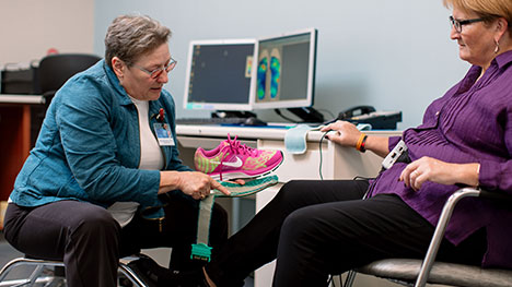 Picture of a Motion Analysis Lab staff member explaining foot pressure test results to a patient.