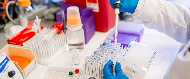 Lab worker pipetting liquid samples into small test tubes