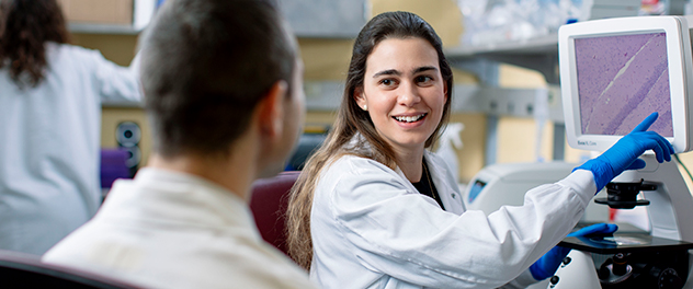 Two research trainees viewing microscopy on a computer screen