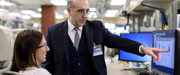 Amir Sadighi Akha, M.D., D.Phil., associate director of the Clinical Immunology and Immunotherapeutics Program, studying research findings on a computer screen with fellow investigator