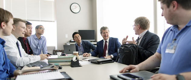 Dr. O'Driscoll and his lab team sitting around a table talking.