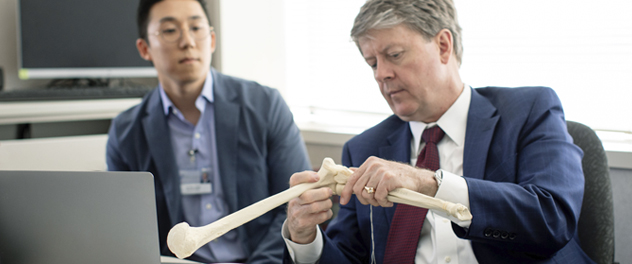 Dr. O'Driscoll and a lab colleague examining an elbow replica.