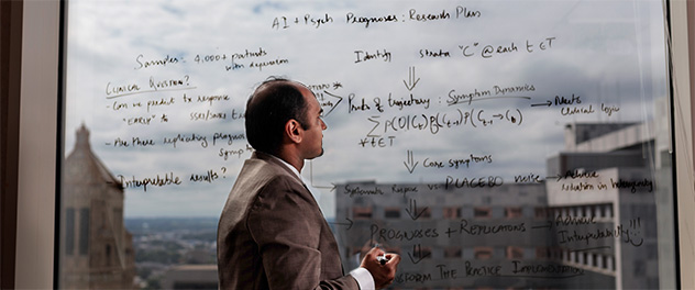 Researcher diagramming ideas on window in foreground, Mayo Clinic buildings in background