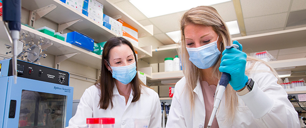 Two researchers in the Lancaster lab conduct biological assays.