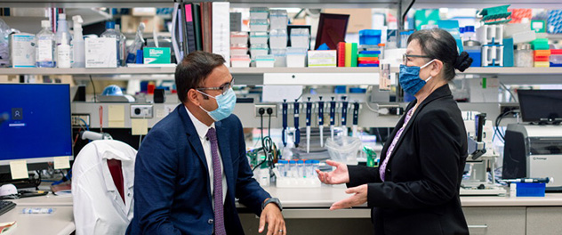 Photograph showing Dr. Majumder seated on the left and Dr. Petersen standing on the right discussing pancreatic cancer research