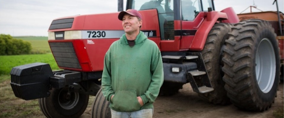 Smiling farmer standing in front of his tractor