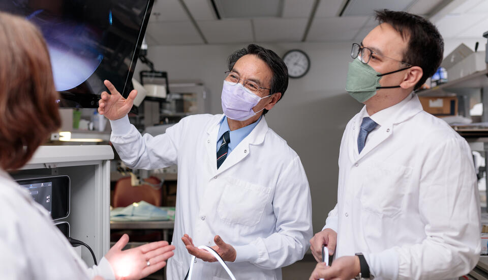 Photograph of Chunfeng Zhao, M.D., and a colleague wearing white lab coats looking at a computer monitor