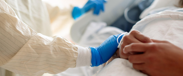 Close-up of gloved hand touching patient's arm