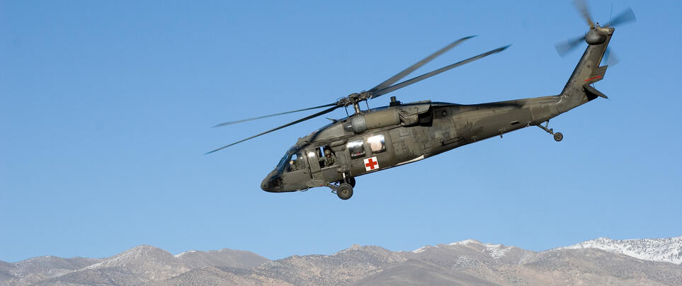 A military helicopter flying over mountains