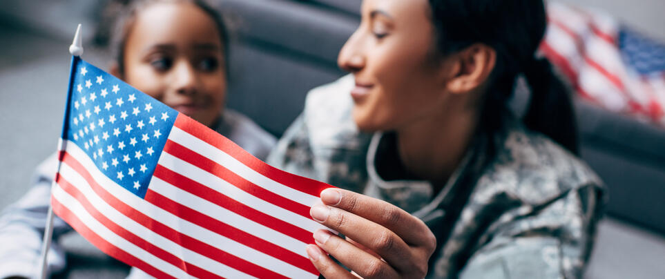 Service member and child holding American flag