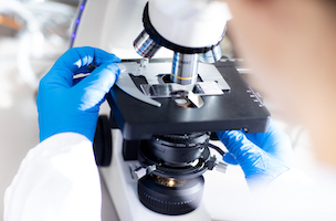 Close-up of lab member using a microscope