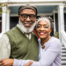 Portrait of senior husband and wife in front of suburban home