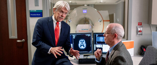 Drs. Ronald Petersen and Clifford Jack Jr. converse outside a procedure room.