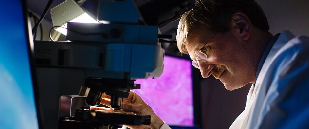 Fergus Couch, Ph.D., examines a slide under a microscope.