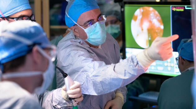 Photograph showing Dr. Bendok in surgical gown and gloves demonstrating surgical techniques