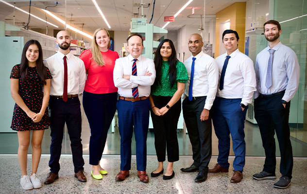 A photograph showing 8 members of the Castro lab team standing together in front of the lab