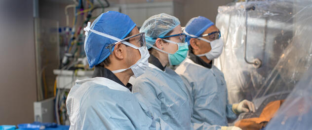 Three healthcare professionals in a catheterization laboratory