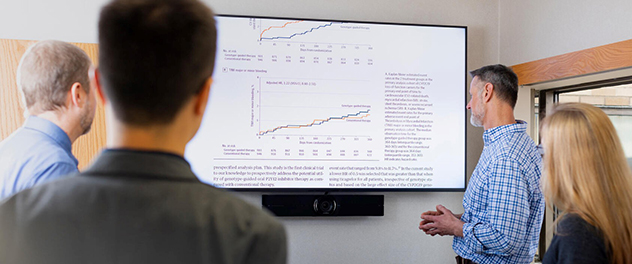 Four people look at graph projected on a screen.